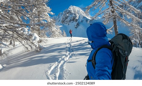 Couple walking in snow shoes with panoramic view of snow capped mountain peak Bielschitza in Karawanks, Bärental, Carinthia, Austria. Ski touring in winter wonderland in the Austrian Alps on sunny day - Powered by Shutterstock