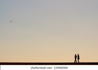 Couple walking at sunset in a harbor - Powered by Shutterstock