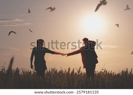 A couple walking through the meadows surrounded by birds in flight