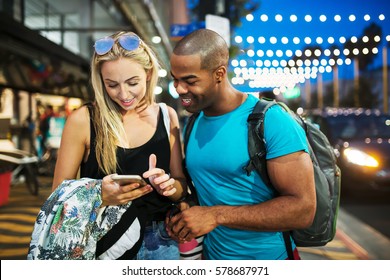 Couple Walking Through Santa Monica At Night Using Smartphone To Find A Directions