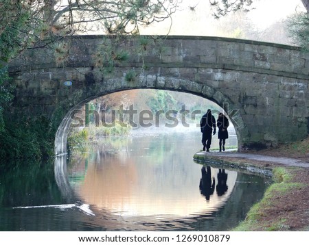 Couple walking under a stone bridge on the Lancaster Canal, Lancashire, England