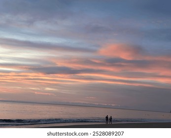 A couple walks hand in hand along the quiet beach, the vast ocean stretching endlessly before them, creating a peaceful and intimate moment. - Powered by Shutterstock