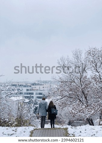 A couple walks and holding hands together at the street during winter season. Winter romance with snow landscapes as a background.