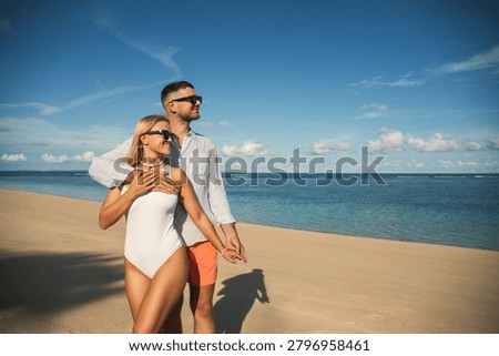 Couple walks on beach while enjoying the sun and sea