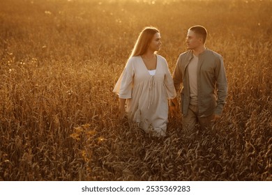 A couple walks through a field of tall grass at sunset. The woman is wearing a white dress and the man is wearing a brown shirt.  - Powered by Shutterstock