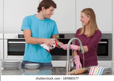 Couple Washing Up The Dishes After The Party