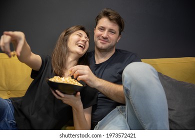 Couple Watching Funny Tv Movie Laughing Lying On Couch With Popcorn. Girlfriend And Boyfriend Watch Love Story, Investigation, Thriller On YouTube Channel. Young Family Evening Entertainment