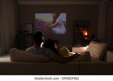 Couple Watching Movie On Sofa At Night, Back View. Space For Text