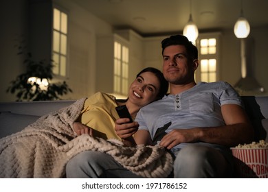 Couple watching movie with popcorn on sofa at night - Powered by Shutterstock