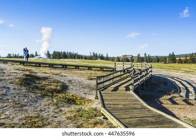 A Couple Watching On  Old Faithful In The Morning,summer, In Yellowstone National Park,usa.