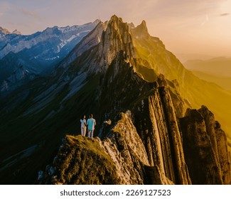 Couple watching the sunset at the edge of a mountain in Switzerland during summer vacation, Schaeffler Altenalptuerme mountain ridge Appenzell Innerrhoden Switzerland