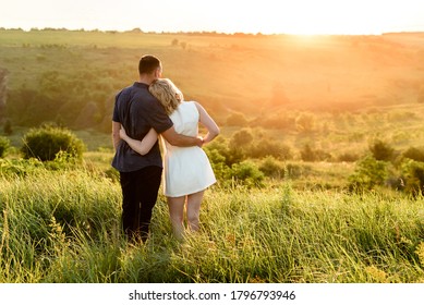 couple watching the sunset in the field . Love 