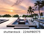 couple watching the sunset in an infinity pool on a luxury vacation in Thailand, man and woman watching the sunset on the edge of a pool in Thailand on vacation