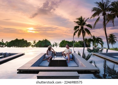 couple watching the sunset in an infinity pool on a luxury vacation in Thailand, man and woman watching the sunset on the edge of a pool in Thailand on vacation - Powered by Shutterstock