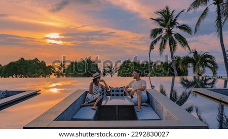 couple watching the sunset in an infinity pool on a luxury vacation in Thailand, man and woman watching the sunset on the edge of a pool in Thailand on a luxury vacation