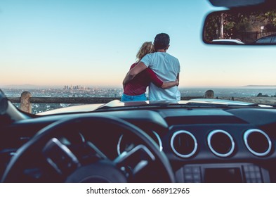 Couple watching sunset from popular view point in Los Angeles, California. Sitting on the sport convertible car hood - Powered by Shutterstock