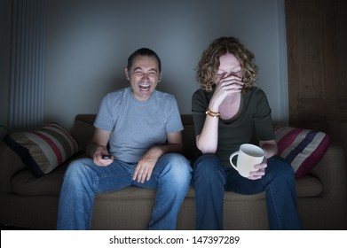 Couple Watching Television Laughing And Embarrassed