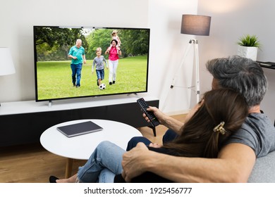 Couple Watching TV Movie On Screen In Room On Couch