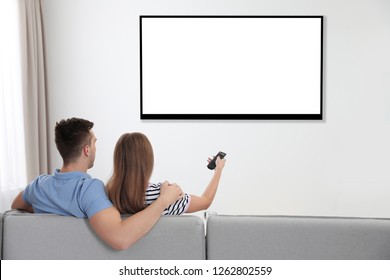 Couple watching TV on sofa at home. Mockup for design