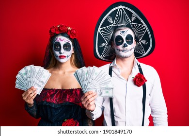 Couple Wearing Day Of The Dead Costume Holding Dollars Thinking Attitude And Sober Expression Looking Self Confident 