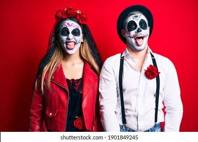 Couple Wearing Day Of The Dead Costume Over Red Sticking Tongue Out Happy With Funny Expression. Emotion Concept. 