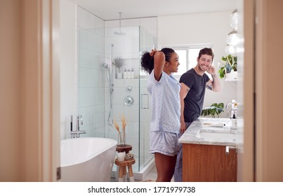 Couple Wearing Pyjamas Standing In Bathroom At Sink Getting Ready In The Morning - Powered by Shutterstock