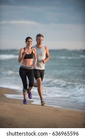 A couple wearing sportswear is running on the beach, the ocean at the background - Shutterstock ID 636965596