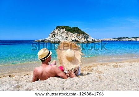 Couple wearing straw sun hat on beach. Summer vacation portrait. Sithonia, Greece.
