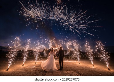 A couple in wedding dresses on the background of fireworks at night.