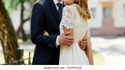 Couple At The Wedding Hugging Hands Close-up Simple Dress Dark Jacket Outdoors On A Sunny Day