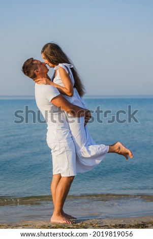 couple in white clothes kissing on the background of the sea