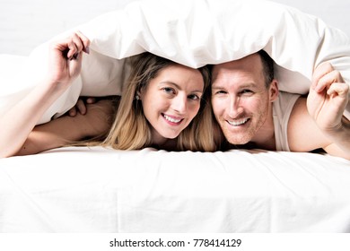 A Couple With White Duvet Over The Head