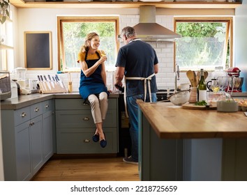 Couple, wine and cooking in kitchen, happy and talking while bonding, conversation and home. Senior, man and woman in retirement with glass, food and together in house with love, romance and laugh - Powered by Shutterstock