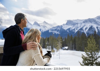 Couple with wine looking at snowy mountain view - Powered by Shutterstock