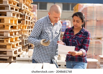 Couple Of Wokers, Man And Woman, Checking Order List At Hardware Store Warehouse