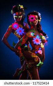 Couple women with glow uv body art and flowers