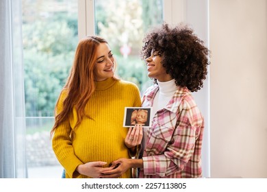 Couple of women presenting the pregnancy photo proud of their future. Concept: maternity, pride, integration - Powered by Shutterstock