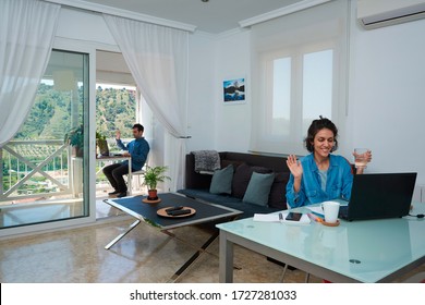 Couple working from home. They are in a bright living room and on the terrace.