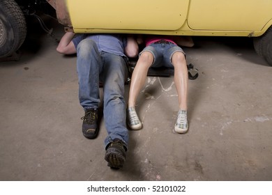 A Couple Working Under A Old Car Restoring It Together With Their Legs Sticking Out.