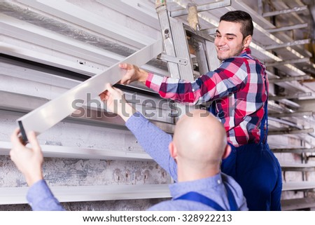 Couple of workmen inspecting window frames at factory indoor