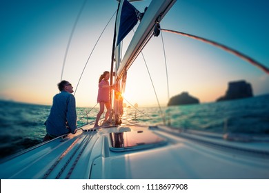 Couple works with ropes on the sail boat at sunset. Tilt shift effect applied