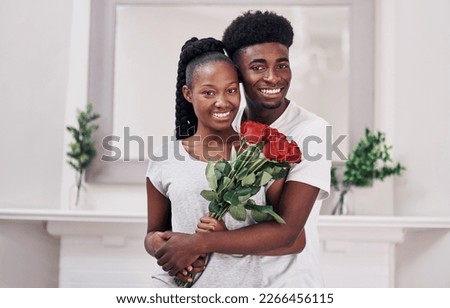 The couple of the year award goes to.... Shot of a young woman holding a bunch of red roses while standing with her boyfriend at home.