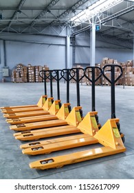 Couple Of Yellow Hand Pallet Trucks In The Warehouse.