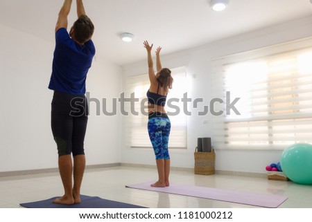 Couple of yogis in urdhva hastasana in bright studio. Young man and woman practicing upward salute yoga pose. Fitness, athletic, workout, exercise, pilates ball, props, healthy lifestyle concepts