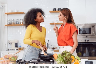 A couple of young girls friends laughing and having fun while cooking, Happy LGBT lesbian couple  cooking together at home - Powered by Shutterstock