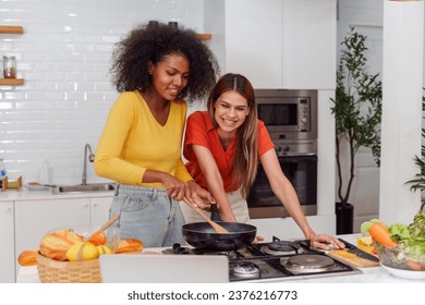 A couple of young girls friends laughing and having fun while cooking, Happy LGBT lesbian couple  cooking together at home - Powered by Shutterstock