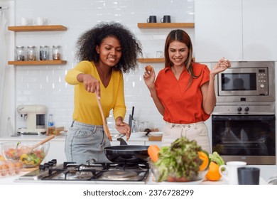 A couple of young girls friends laughing and having fun while cooking, Happy LGBT lesbian couple  cooking together at home - Powered by Shutterstock