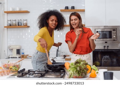 A couple of young girls friends laughing and having fun while cooking, Happy LGBT lesbian couple  cooking together at home - Powered by Shutterstock