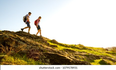 Couple of Young Happy Travelers Hiking with Backpacks on the Beautiful Rocky Trail at Warm Sunny Evening. Family Travel and Adventure Concept. - Shutterstock ID 1079578931