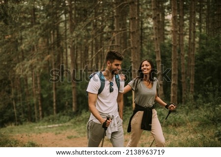 Couple of young hikers with backpacks walk through the forest